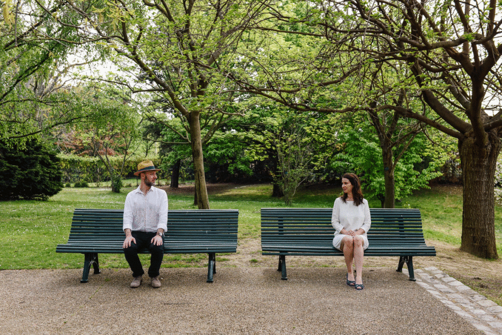 Un homme et une femme sont assis sur deux bancs dans un parc