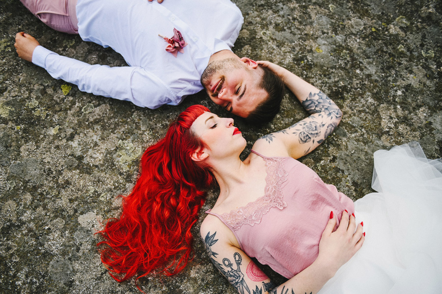 un couple avec tatouages est allongé sur un rocher