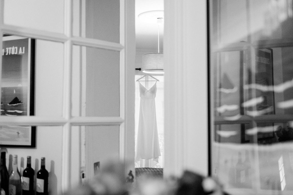 La robe de la mariée apparaît dans l’embrasure d’une porte