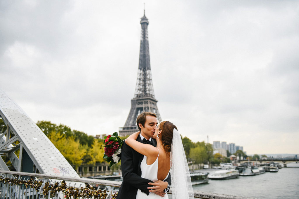 Un couple de jeunes mariés s’embrasse devant la Tour Eiffel à Paris