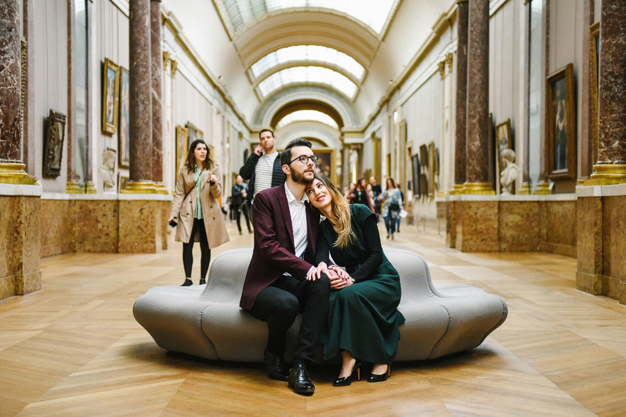 un couple s'enlace dans une galerie du musée du Louvre