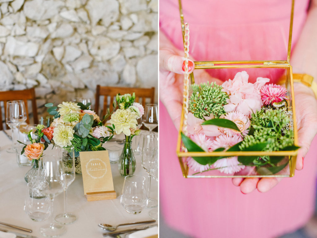 Des fleurs colorées sont présentées sur une table d'un dîner de mariage, et une femme tient une boîte remplie de fleurs roses et des alliances des mariés